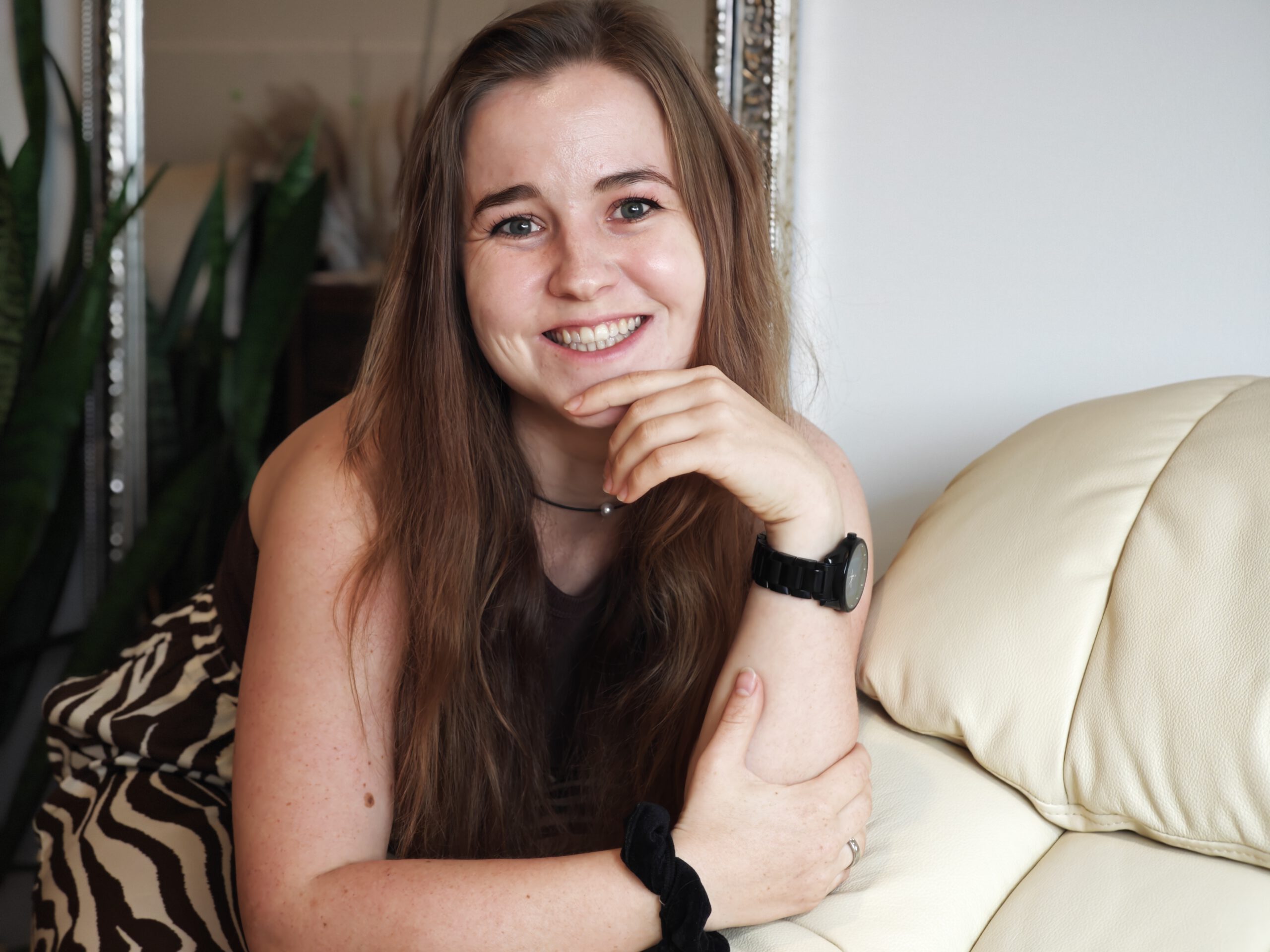 ich_2 junge Frau mit langen Haaren im Portrait (ich), lächelnd, lehre auf meinem Therapiesessel in meiner Praxis